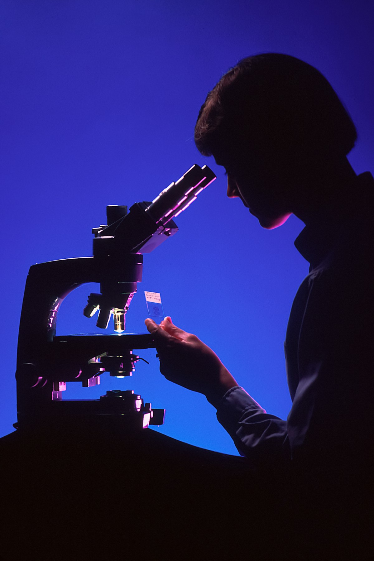 Silhouette of a scientist using a microscope in a dark laboratory